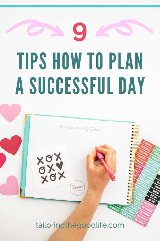 Flat lay: big notebook, stickers, and a hand that is writing in the notebook with a pink pen - how to plan your day