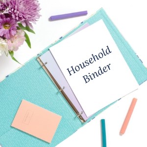 blue Household Binder laying flat on a white table with flowers and 3 pens