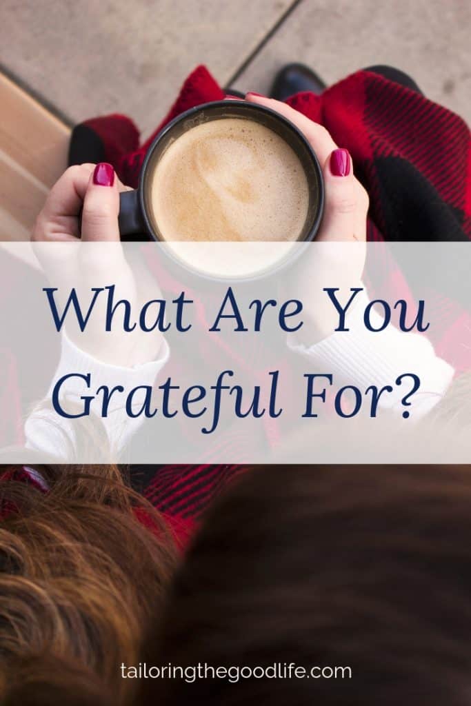 lady in a cozy dark red scarf with a cup of coffee thinking about gratitude journal prompts