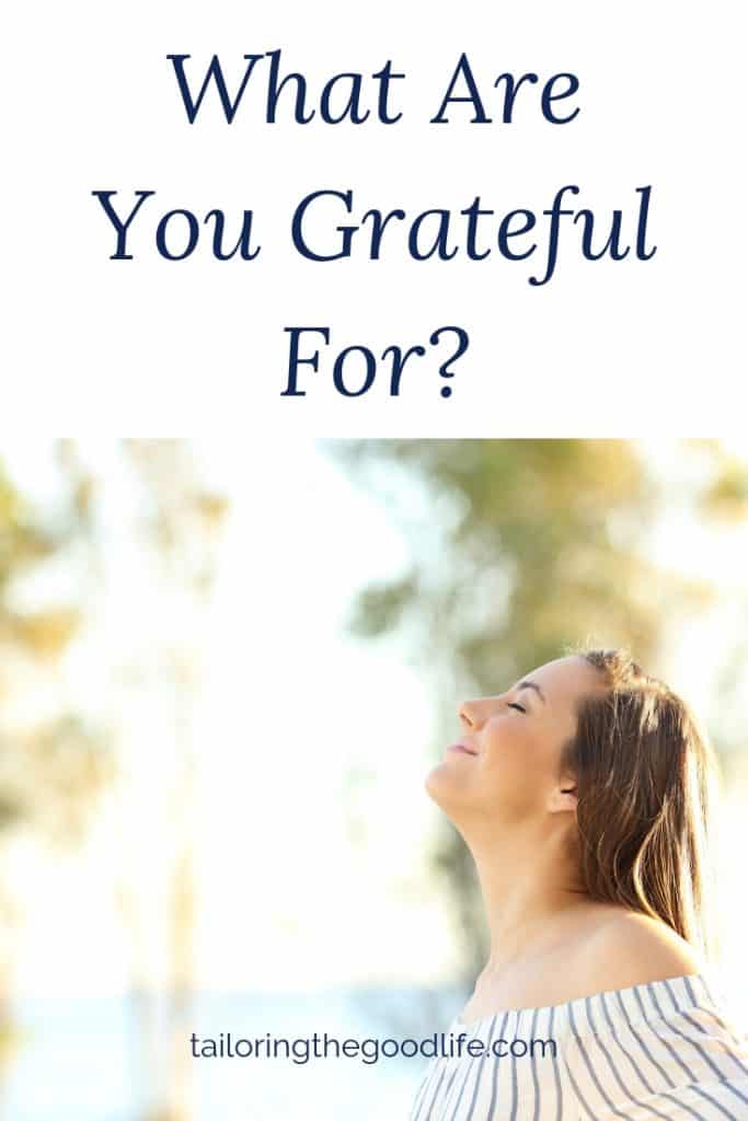 smiling woman looking up with her eyes closed thinkg about gratitude journal prompts