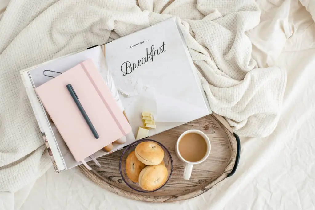 slept-in-bed with a tray with coffee, buns, a book, and a notebook - productivity improvement